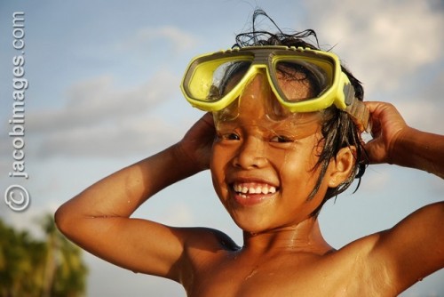 A local girl swimming with goggles smiles in the late evening sun A local girl swimming with goggles smiles in the late evening sun