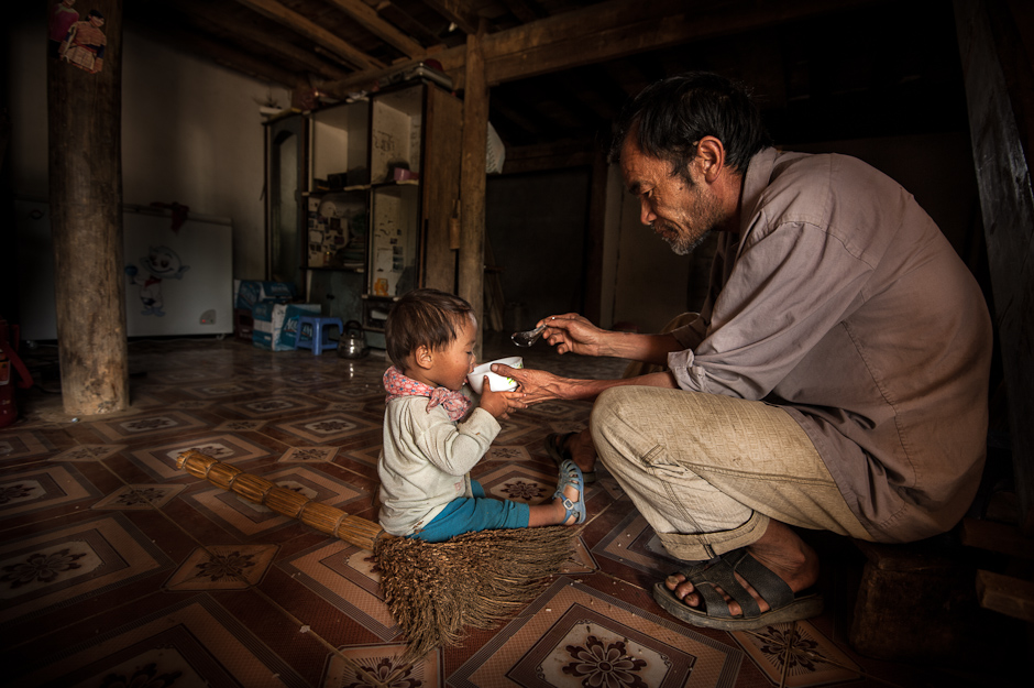 A Hmong man feeding his child